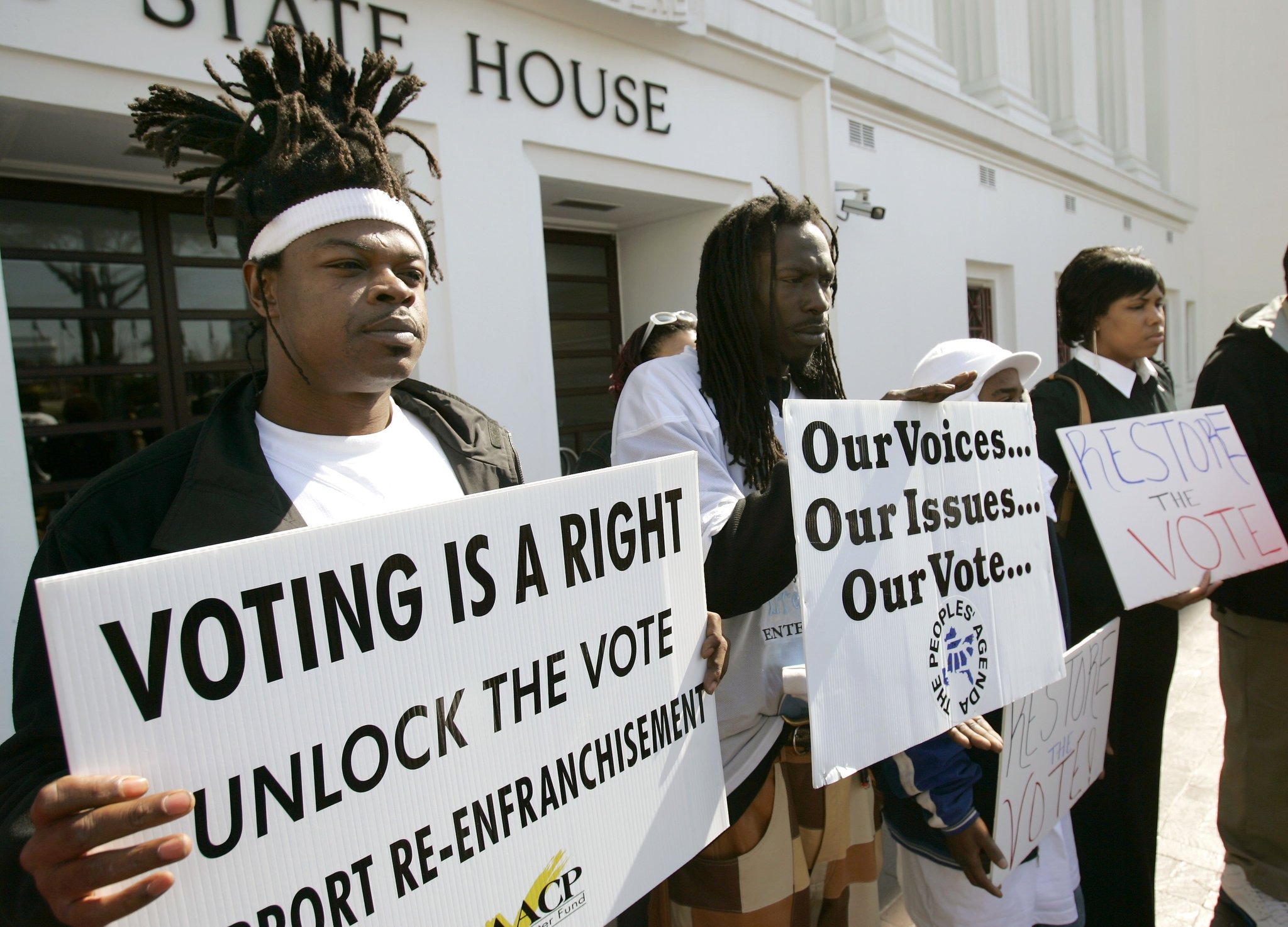 Protesters hold signs about unlocking their vote and supporting re-enfranchisement